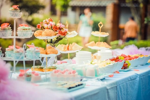 27 Bridal Shower Ideas That Feel Fresh, Fun, and Actually Personal 1 Outdoor wedding reception dessert table decorated with flowers, featuring pastries, cupcakes, fresh fruit, and elegant tiered stands