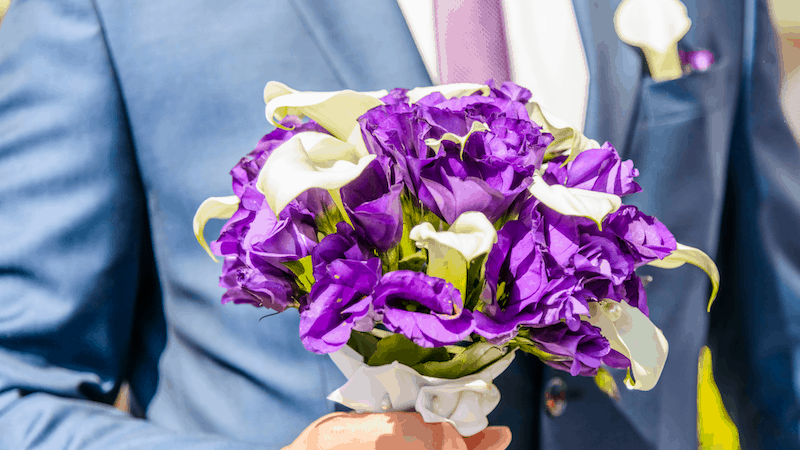 Who Is In A Wedding Party? 3 Purple and white flower bouquet held by a groomsman