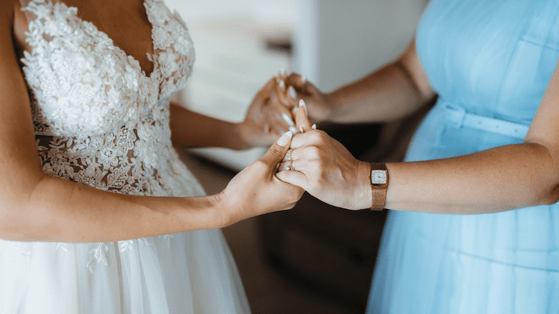 Bride and mother holding hands together