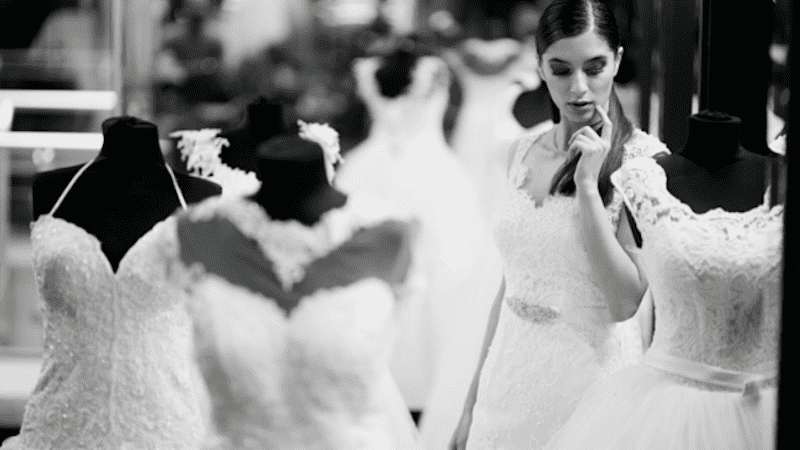 Bride admiring wedding dresses display.