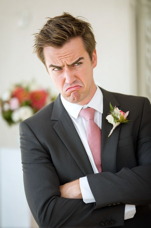 Grumpy Groom in a suit with a flower boutonniere.