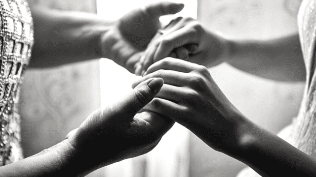 How to Deal With Parents Controlling Wedding Planning 3 Close-up black and white photo of bride and mother of the bride holding hands tenderly, symbolizing love and connection at a wedding