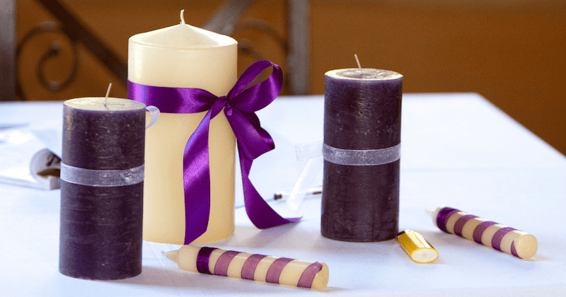 Wedding Ceremony Checklist: A Comprehensive Guide 1 Three wedding unity candles, one wrapped in purple ribbon and two in deep plum, displayed on a white table