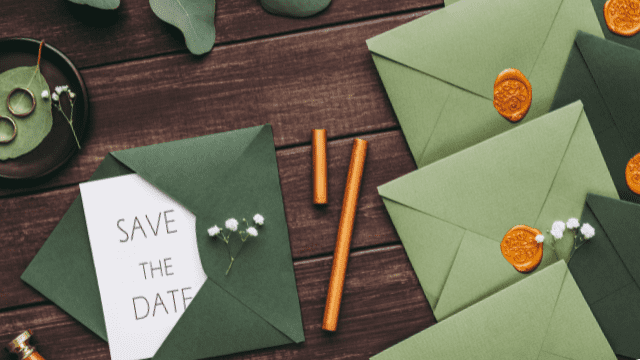 17 Hidden Wedding Costs You May Not Have Anticipated 2 Green wedding envelopes with orange wax seals and a “Save the Date” card styled with gold accents on a rustic wood table.