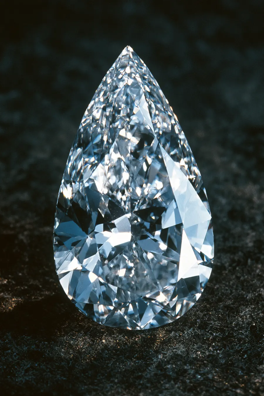 12 Engagement Ring Cuts and Diamond Shapes Compared 5 Pear cut diamond on a dark textured surface