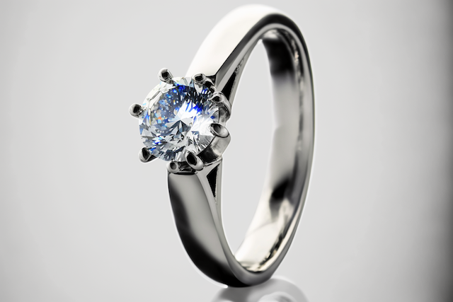 Platinum engagement ring with round brilliant diamond solitaire in six prong setting on light gray background