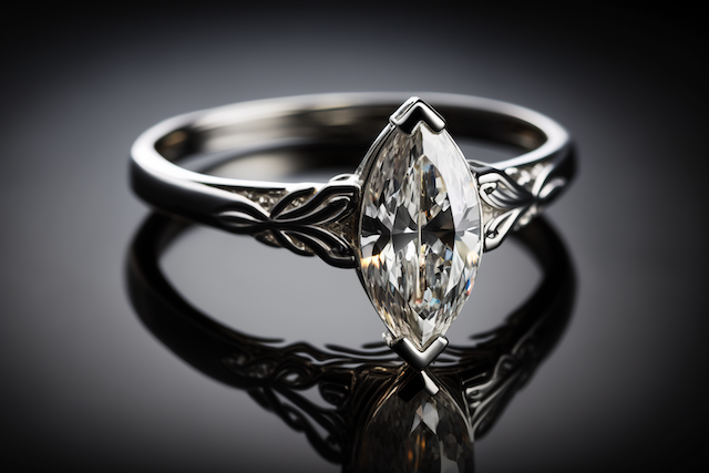 White gold engagement ring with marquise cut diamond and intricate engraved band on black reflective surface