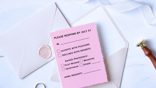Wedding RSVP Questions: The Ultimate List 3 Pink wedding RSVP card with meal choices and song request beside white envelope, wax seal, ribbon, and stamp on light background