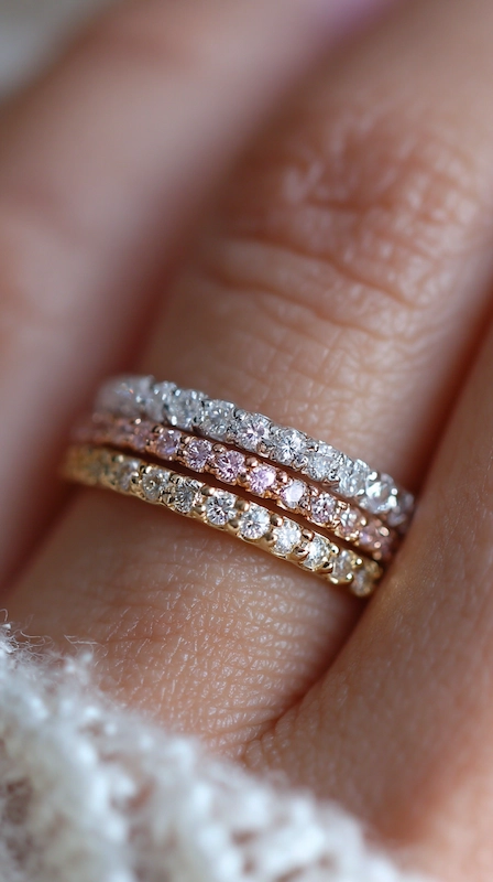 Non-Traditional Engagement Rings: Say Yes To A New Trend 10 Stacked pavé diamond wedding bands in white, rose, and yellow gold on finger, showcasing delicate sparkle and layered styling