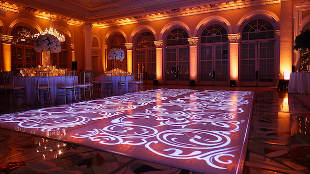 Customized Dance Floor Elegant wedding reception ballroom with warm amber lighting and a custom illuminated dance floor featuring intricate white swirl patterns