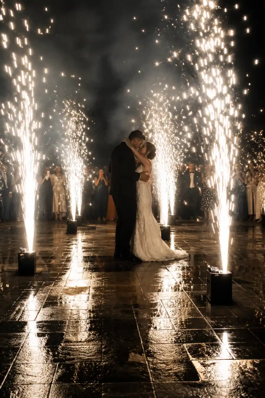 33 Jaw-Dropping Ways to Wow Your Wedding Guests at the Reception 4 Newlyweds watch pale and gilt fireworks fill the night sky over a wet stone terrace at their wedding celebration at midnight