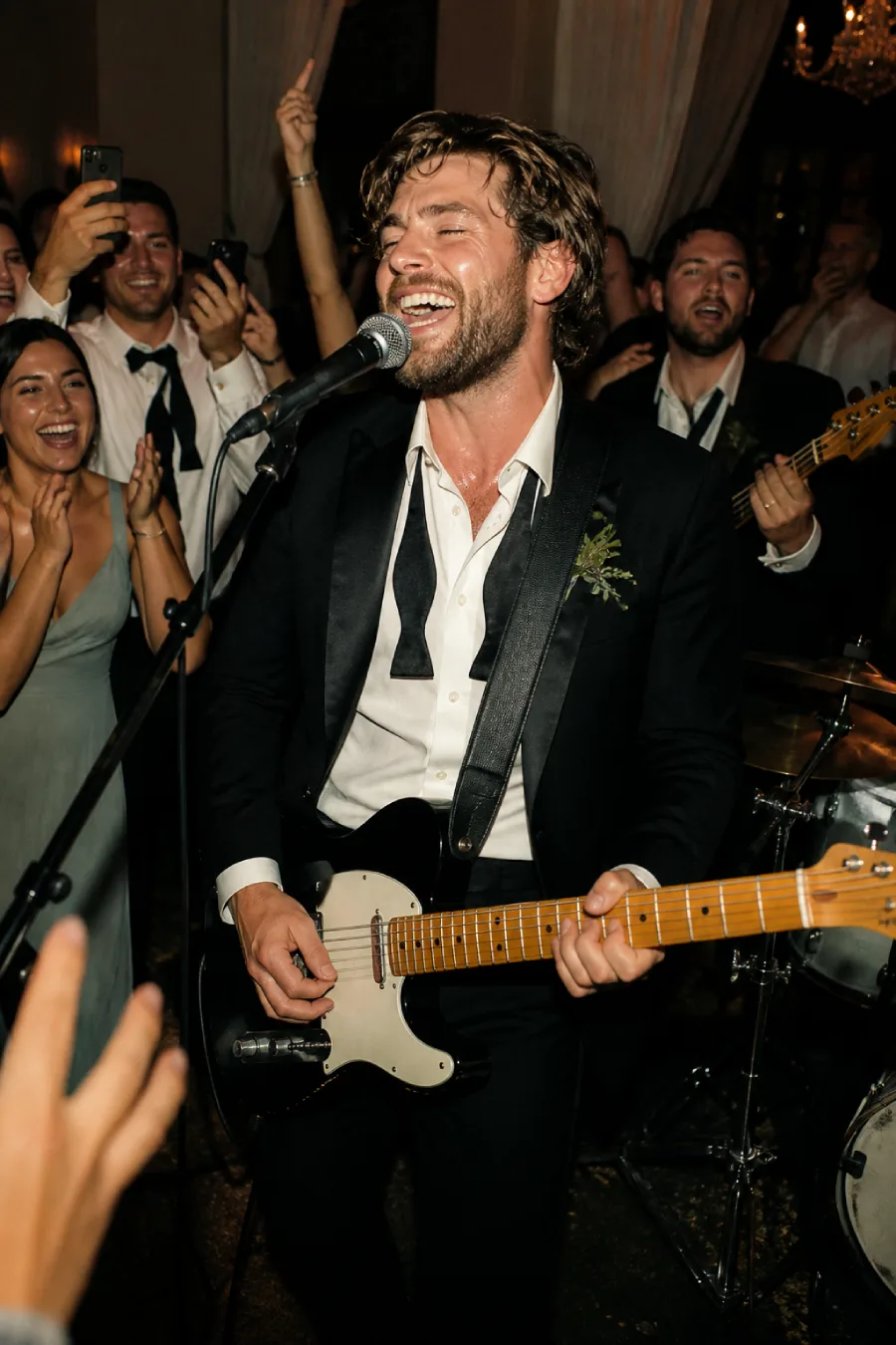 33 Jaw-Dropping Ways to Wow Your Wedding Guests at the Reception 8 The groom sings and plays electric guitar on the reception dance floor while friends and musicians cheer around him with joy.