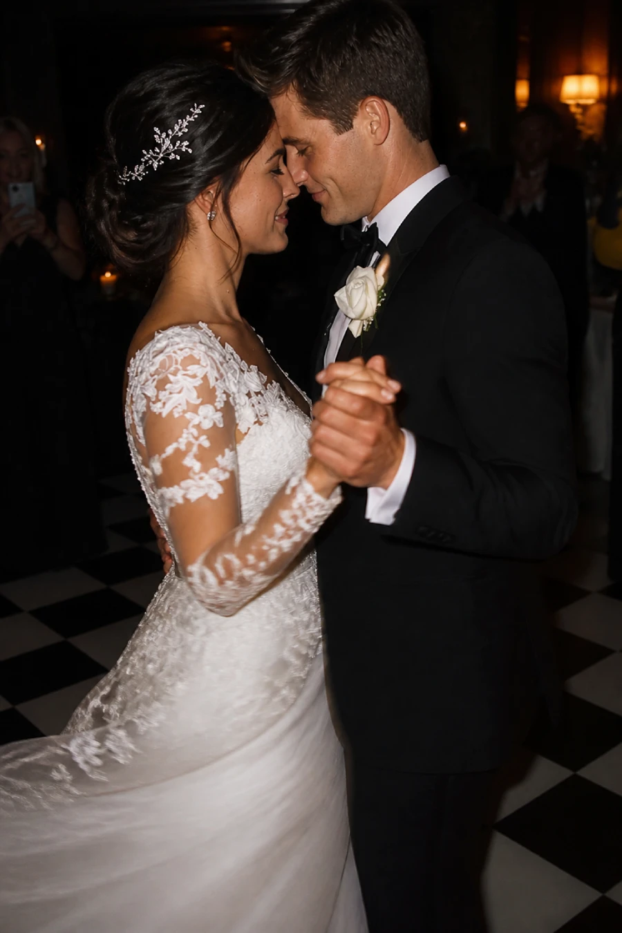33 Jaw-Dropping Ways to Wow Your Wedding Guests at the Reception 6 Newlyweds share an intimate first dance on a checkerboard floor while warm lamps glow around the dark reception room at dusk.