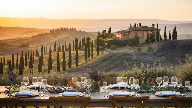 Elegant Italian-inspired wedding reception with a rustic table set against rolling Tuscan hills, adorned with flowers and wine glasses