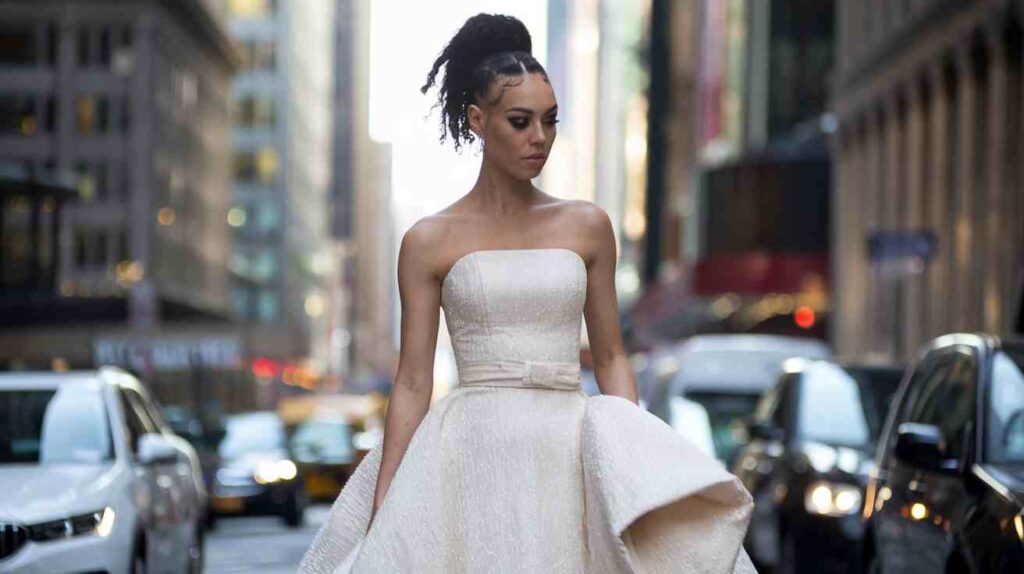 Textured High Ponytail Bride in strapless gown on a city street, Textured High Ponytail with defined edges and curls, modern editorial vibe and confident, elegant pose.