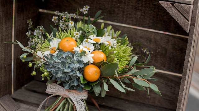 Citrus-inspired Bridal Bouquet Citrus-inspired wedding bouquet with fresh oranges, daisies, and greenery tied with twine for a bright, rustic summer wedding look