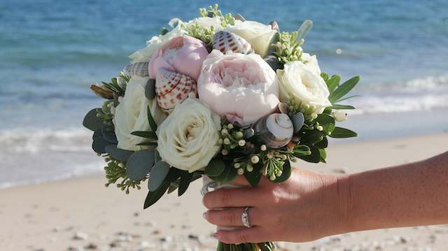 Seashell and Flower Mix Bridal Bouquet Seashell and flower bridal bouquet with white roses, blush peonies, and beach-inspired seashells for a coastal wedding look.