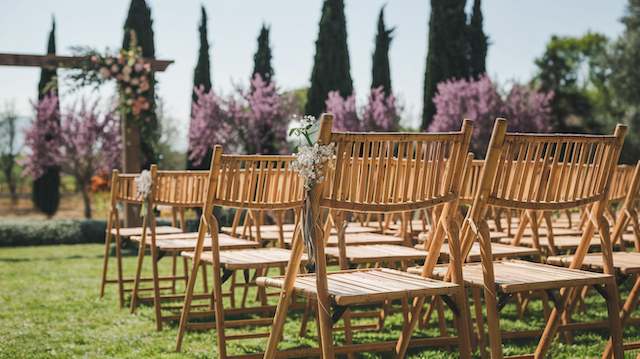 Bamboo Folding Chairs Rows of bamboo folding chairs set up for an outdoor wedding, surrounded by greenery and pink blossoms, creating a rustic ambiance.