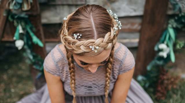 Braided Crown for Rustic Weddings Bridesmaid wearing a braided crown halo with baby’s breath accents, shown from above with two long braids and a lavender lace dress.