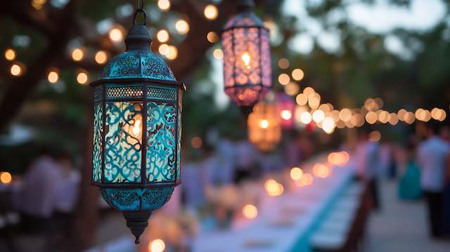 Moroccan Lanterns Hanging Moroccan lanterns with intricate colorful glass glowing above a long outdoor wedding table lined with candles and string lights at dusk.