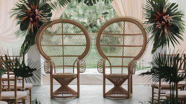 Peacock Chairs Peacock chairs for weddings, featuring intricate rattan design and surrounded by tropical greenery, create a bohemian-style setting.