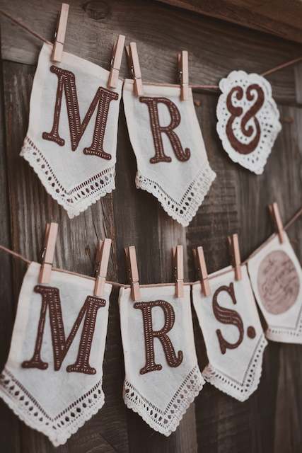Upcycled Fabric Banners Fabric banner with "Mr & Mrs" in bold letters, hung on a rustic wooden background using clothespins, creating a charming and personalized decoration.