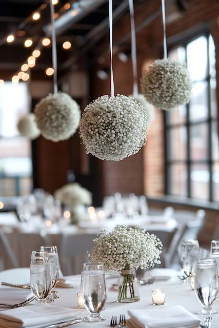Baby’s Breath Kissing Balls Suspended Mid-Air Hanging baby’s breath spheres suspended above wedding reception tables, creating a whimsical and romantic atmosphere with soft lighting