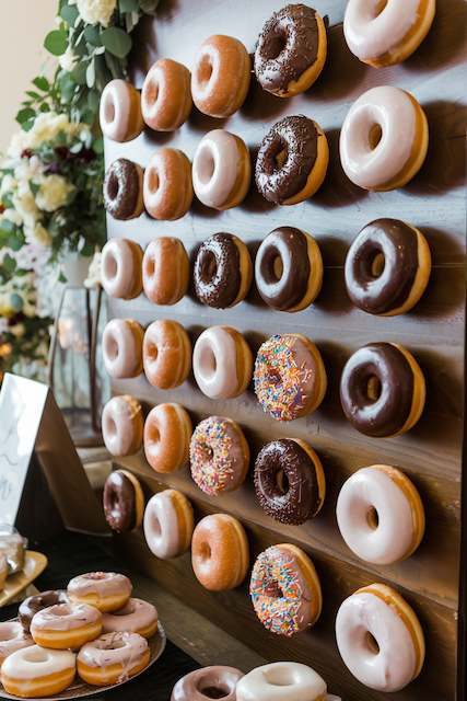 Donut Wall Donut wall with assorted glazed chocolate and sprinkle donuts at a wedding reception
