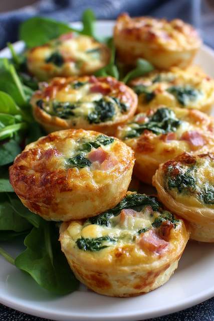 Mini Quiches Mini ham, cheese, and spinach quiches arranged on a bed of fresh greens — a perfect bite-sized option for a brunch wedding menu