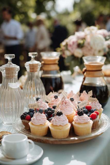 Dessert and Coffee Bar Only Event Cupcakes topped with fresh berries displayed on a dessert table alongside artisan coffee carafes at an outdoor wedding reception