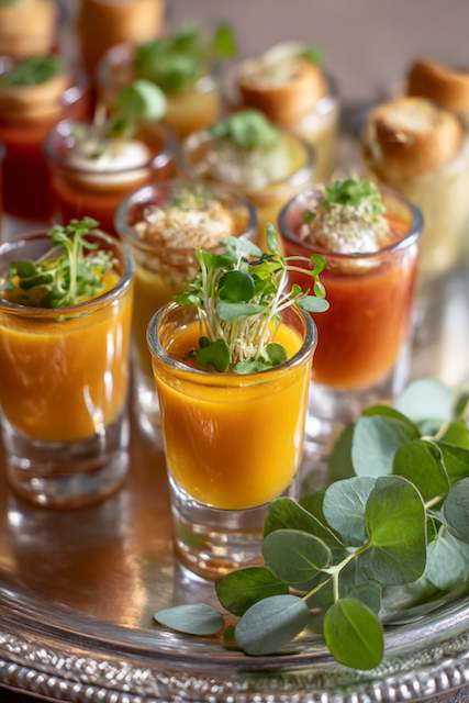 Seasonal Soup Shooters A selection of vibrant soup shooters elegantly garnished, served in small glasses, ideal for a chic wedding cocktail hour.