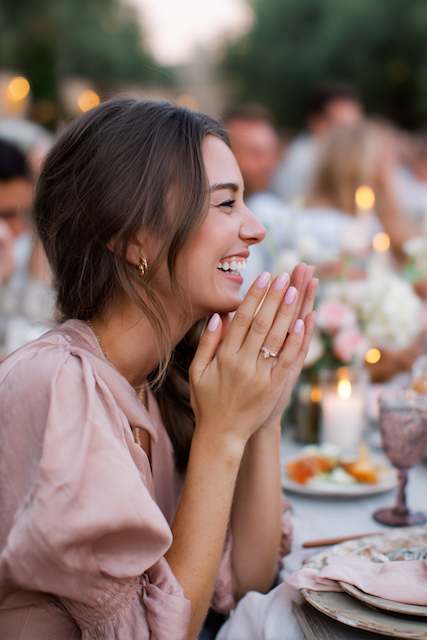 bridesmaid with ligh pink nail polish Bridesmaid with pearl hairpin, smiling and clapping at rehearsal dinner table