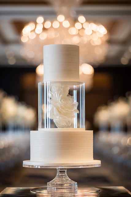 Acrylic tier spacer wedding cake Elegant wedding cake with acrylic tier spacers and a stunning white floral sculpture encased in clear glass
