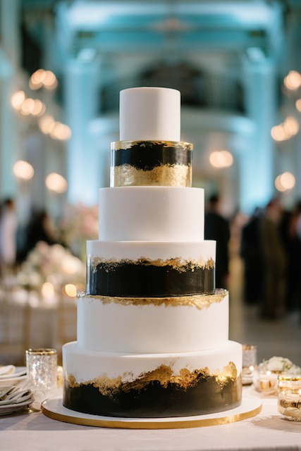 Black and gold wedding cake Five tier wedding cake with alternating white and black fondant bands accented by gold leaf detailing, creating a bold, modern luxury statement.