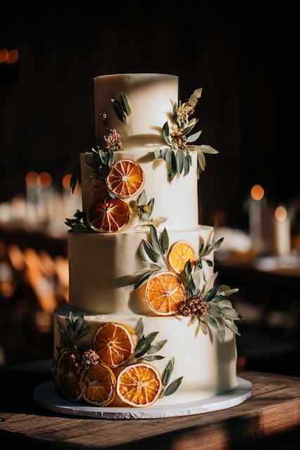 Dried citrus + foliage decor wedding cake Three-tier wedding cake adorned with dried citrus slices and eucalyptus leaves, creating a rustic and elegant design