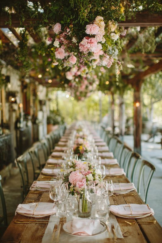 Spring Country Wedding Country-themed wedding setup with rustic tables, pink drapery, and greenery for a romantic outdoor celebration