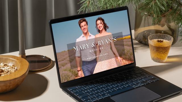 wedding website displayed on laptop image of a laptop displaying Mary and Ryan's wedding website with a cozy setup including pine branches and a glass of tea nearby