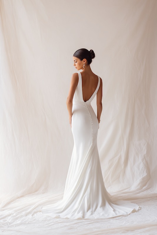 Petite Bride in mermaid wedding dress Bride in a stunning, backless wedding dress with delicate buttons running down the train, showcasing a sleek mermaid silhouette