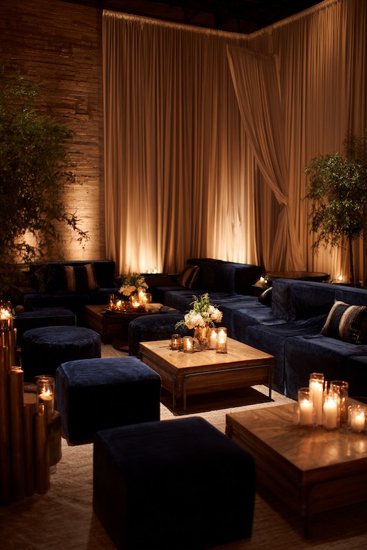 Elegant wedding cocktail lounge with navy velvet seating, wooden tables, and soft candlelight