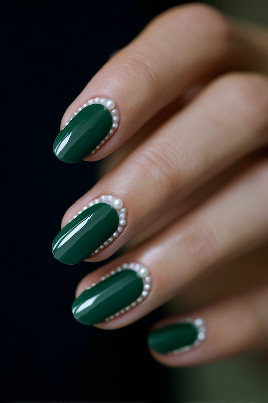 Hand with glossy dark green nails outlined in tiny pearl accents, creating a bold and elegant manicure look. Hand with glossy dark green nails outlined in tiny pearl accents, creating a bold and elegant manicure look.