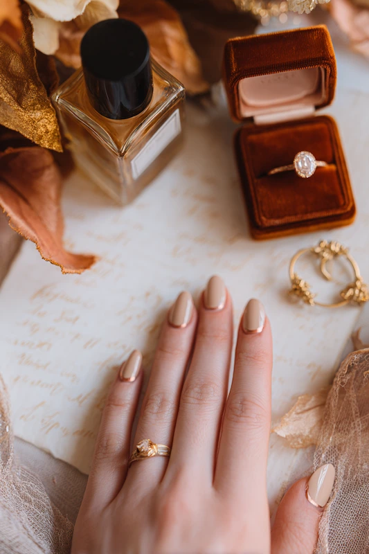 Neutral beige almond nails with a glossy finish, styled with gold rings and a velvet ring box — a timeless, elegant bridal look Neutral beige almond nails with a glossy finish, styled with gold rings and a velvet ring box — a timeless, elegant bridal look