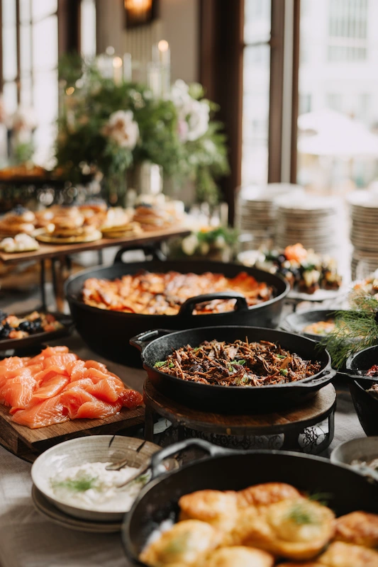 25 Wedding BBQ Buffet Ideas That Instantly Upgrade Your Reception 26 Elegant wedding brunch buffet with cast iron skillets, smoked salmon, potato cakes and garnishes, florals in background