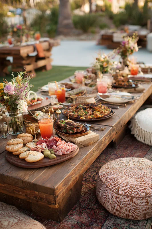 25 Wedding BBQ Buffet Ideas That Instantly Upgrade Your Reception 12 Low boho wedding table with grazing boards, pink drinks, wildflower bud vases, and floor cushions for relaxed outdoor dining