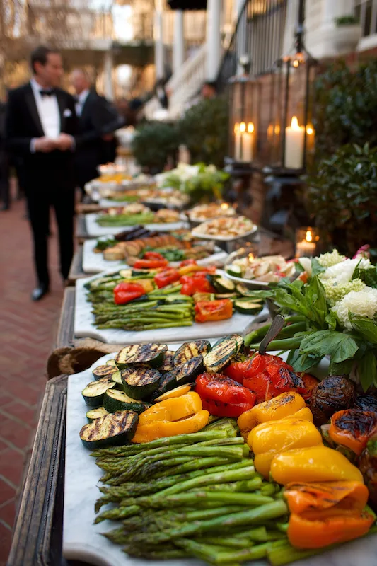 25 Wedding BBQ Buffet Ideas That Instantly Upgrade Your Reception 14 Grilled veggie wedding station with colorful asparagus, peppers, zucchini, and mushrooms on rustic platters, elegant candlelit setup
