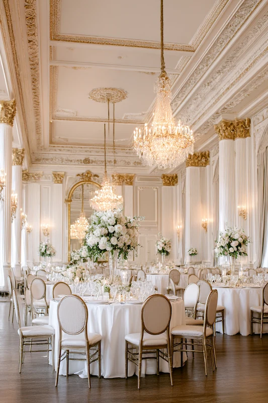 Old Money Wedding Aesthetic: Your Complete Style Guide 10 Elegant ballroom wedding reception with tall white floral centerpieces, gold detailing, crystal chandeliers, and round tables with ivory linens