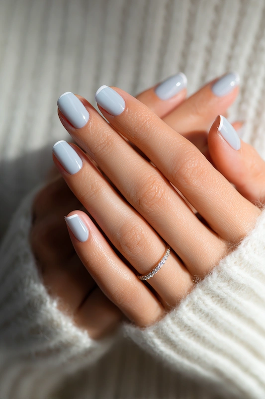 Macro close-up of hands with soft powder blue short square nails, glossy finish, thin diamond band, cozy knit background