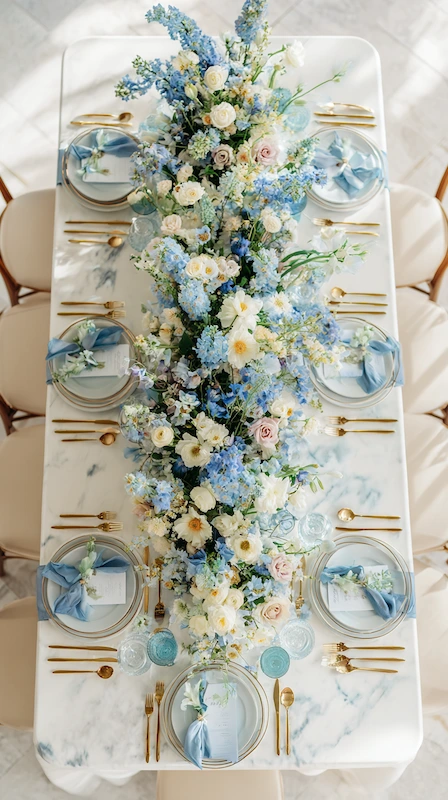 35 Spring Wedding Centerpieces With Flower Pairings Brides Can Actually Use 28 Elegant blue and white wedding table runner centerpiece with soft florals, gold flatware, and marble tabletop place settings