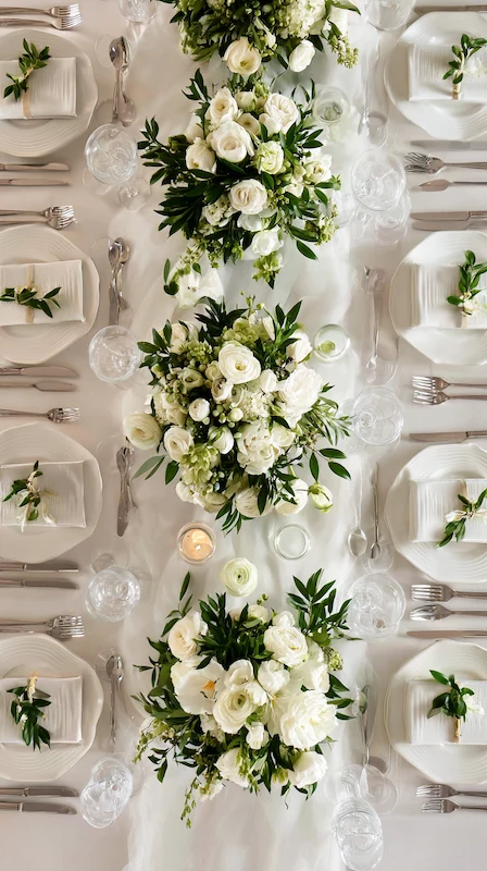 35 Spring Wedding Centerpieces With Flower Pairings Brides Can Actually Use 30 Classic white wedding table with lush rose and greenery centerpieces arranged in a clean runner style with elegant place settings