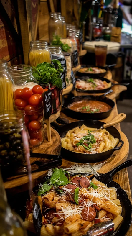25 Wedding Pasta Bar Ideas Your Guests Will Obsess Over 11 Rustic wedding pasta bar with skillet dishes, fresh toppings in jars and herbs displayed on wooden tables for guests to customize