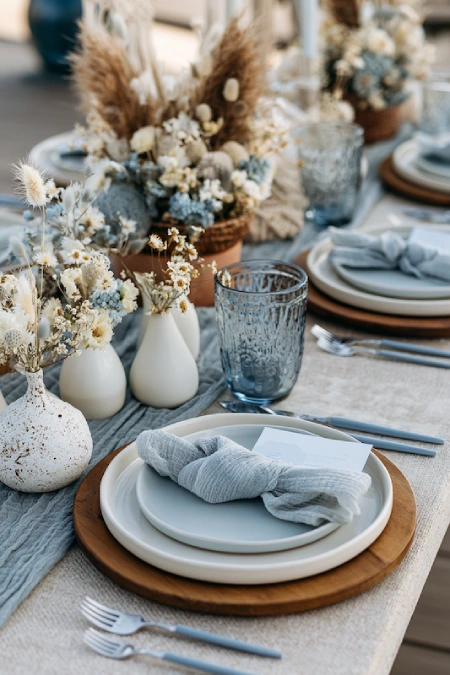 Dusty Blue Wedding Decor: Florals, Table Settings and Reception Styling 18 Boho dusty blue wedding tablescape with dried florals, wood chargers, textured linens, and soft neutral reception styling.